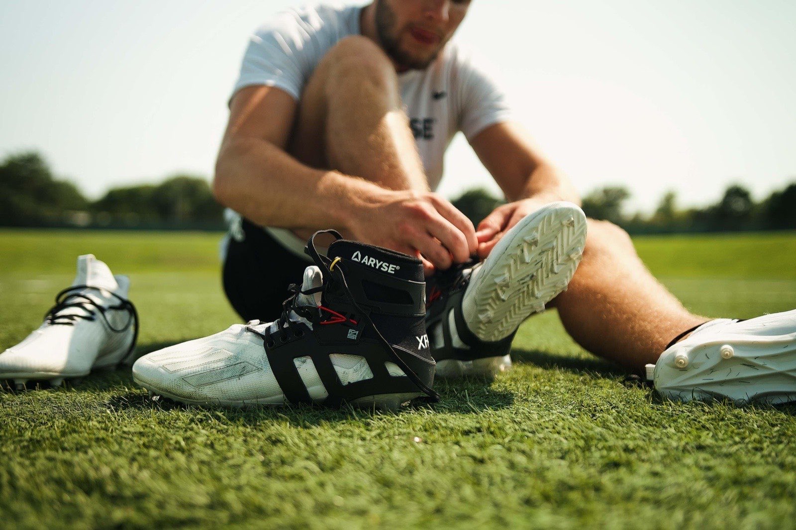 Athlete fastening an ARYSE ankle brace on a sports field